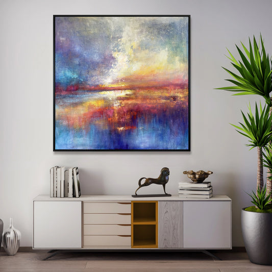 a large abstract painting hanging on a wall above a white cabinet with drawers. The painting has a vibrant and colorful composition, with a mix of blue, orange, and purple hues. The cabinet below the painting has a few books and a small statue of a horse. The room also includes a potted plant and a vase, adding to the overall aesthetic of the space.