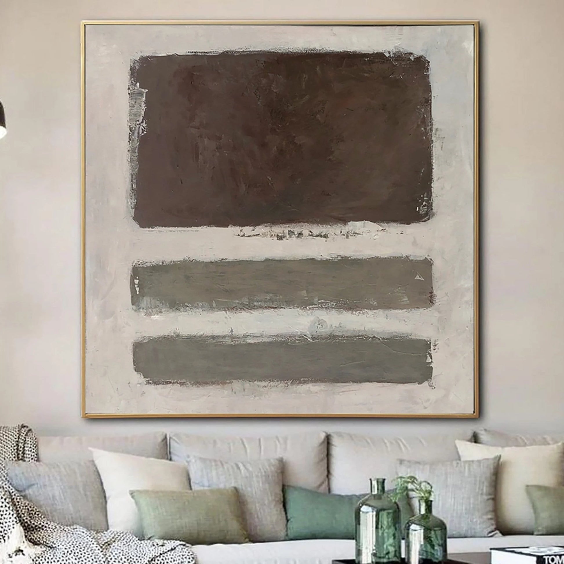 a large abstract painting hanging on a wall above a couch with white and gray pillows.