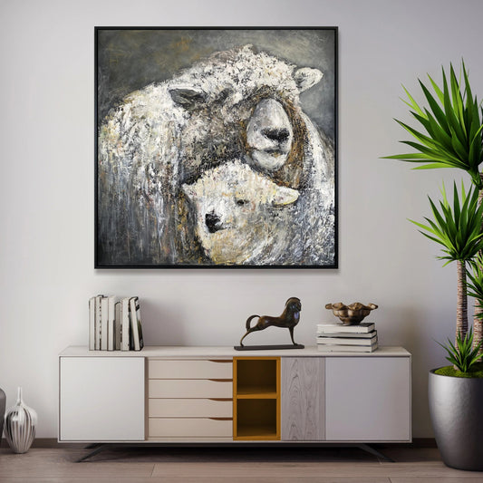 a large painting of two sheep, one white and one brown, hanging on a wall above a white cabinet with drawers. The cabinet also has a small figurine of a horse on top of it. The wall behind the cabinet has a plant, and there are several books and decorative items on the cabinet.