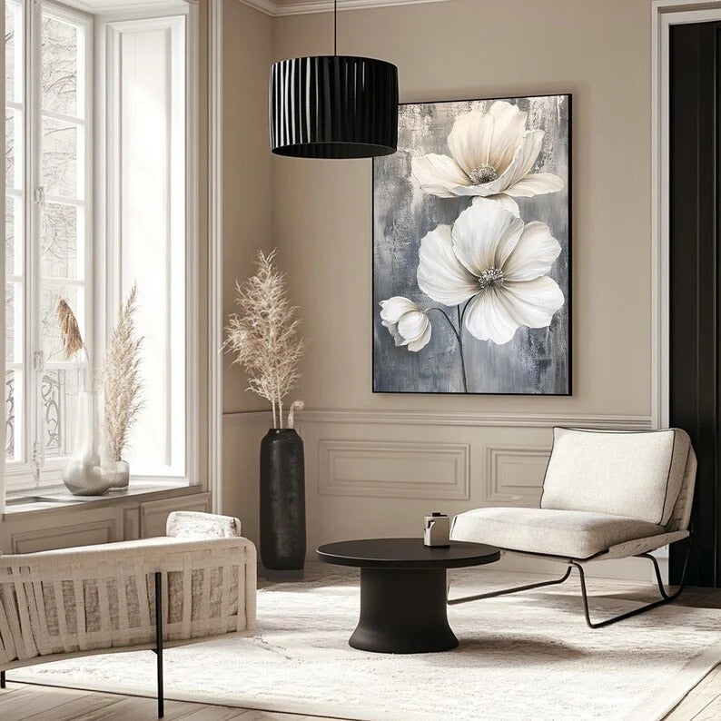 a modern living room with a large floral painting on the wall, a black coffee table, a white sofa, and a black pendant light.