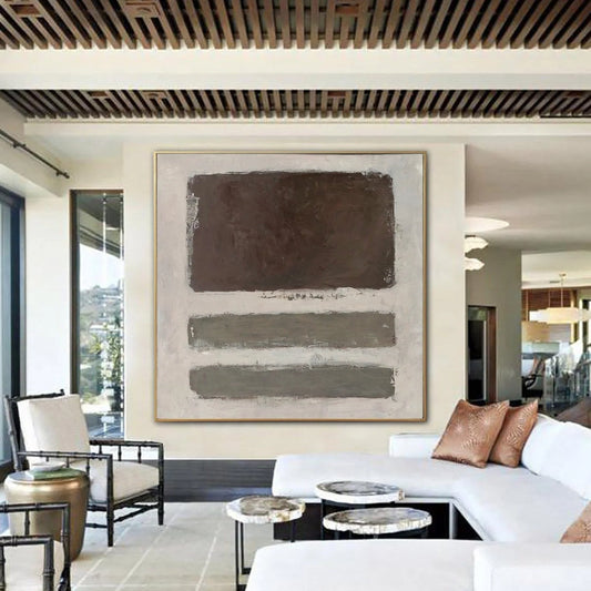 a modern living room with a large abstract painting on the wall, a white sofa, a black chair, and a coffee table with decorative items.
