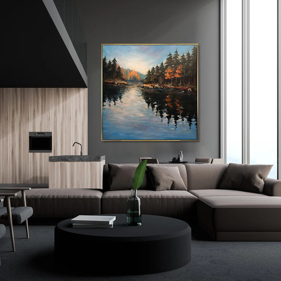 a modern living room with a large painting of a serene lake scene hanging on the wall. The painting is framed in gold and is the focal point of the room. The room has a neutral color scheme with a gray sofa, a black coffee table, and a wooden accent wall. The overall design creates a calm and inviting atmosphere.