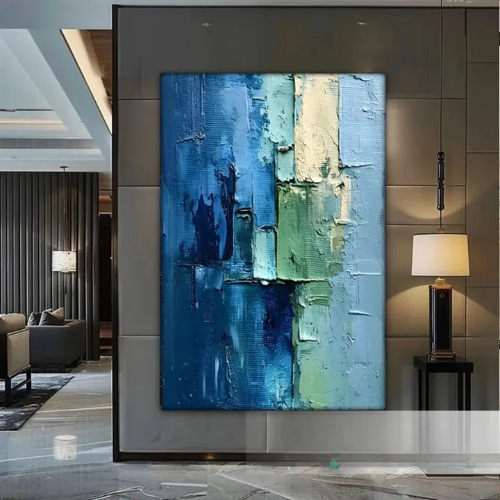 a large abstract painting with a blue and green color palette, displayed on a wall in a modern living room setting.