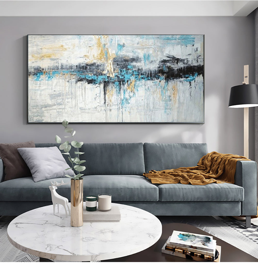 a living room with a gray couch and a painting on the wall