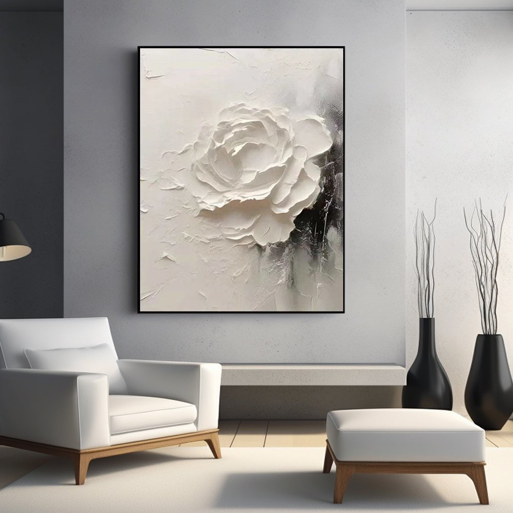 a modern living room with a large white flower painting hanging on the wall above a white armchair. The room has a minimalist and elegant design, with a wooden floor and a white ottoman in the foreground.