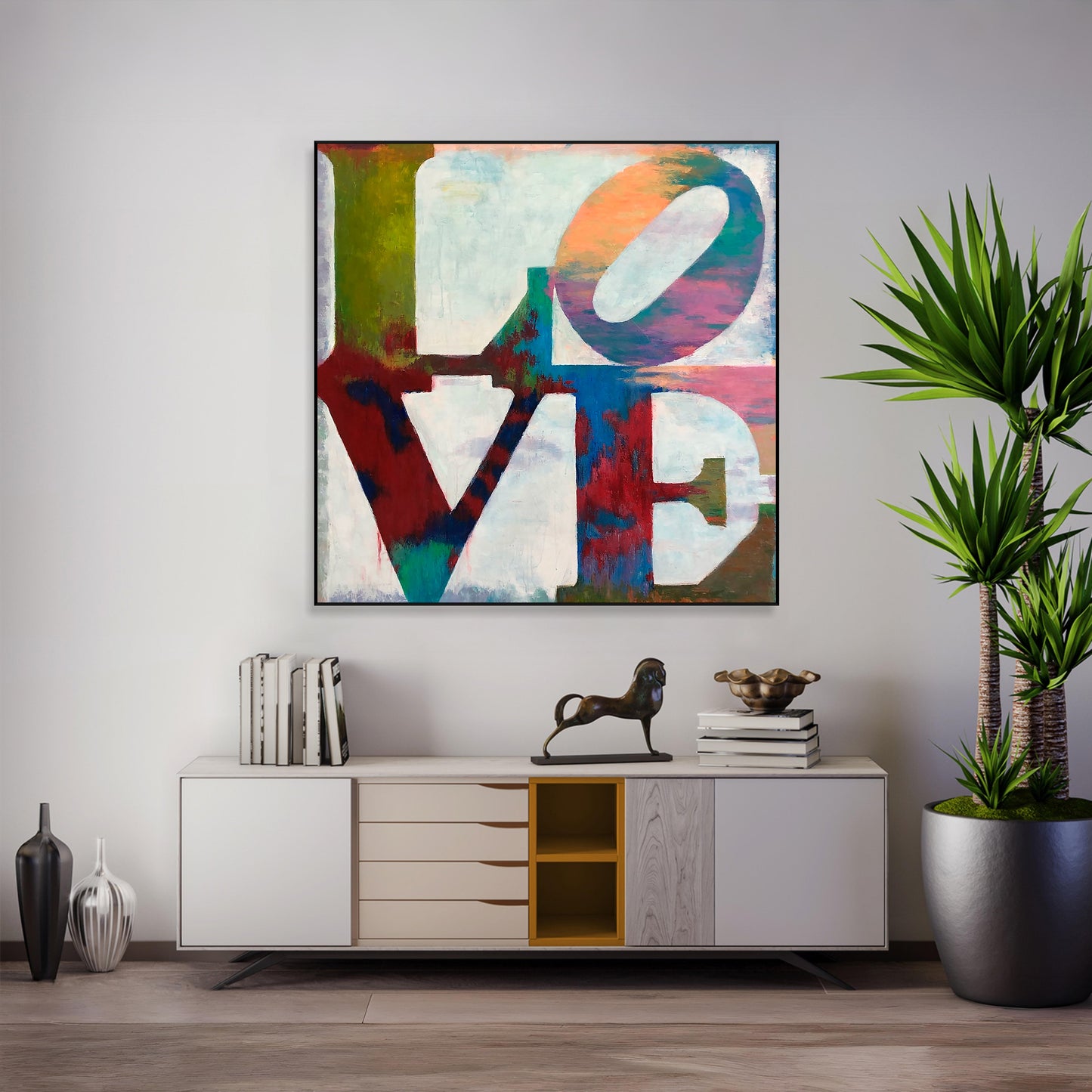 a modern living room with a large abstract painting of the word "LOVE" hanging on the wall above a white cabinet with drawers. The cabinet has a decorative metal sculpture on top. The room also includes a potted plant, books, and other decorative items, creating a stylish and comfortable atmosphere.