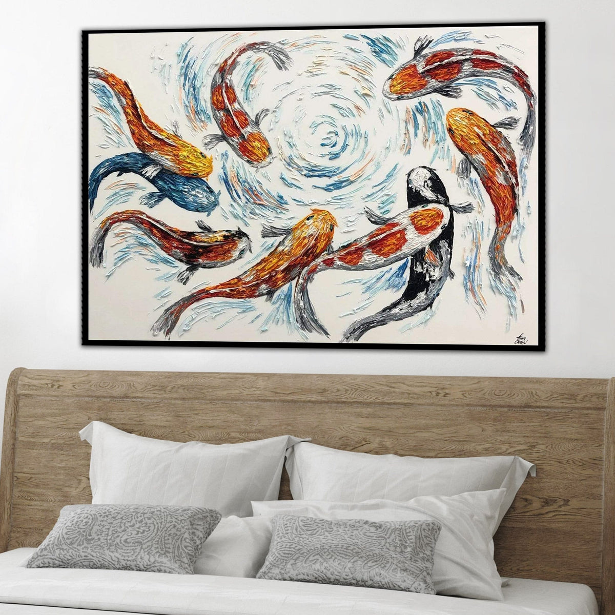 a large painting of colorful fish swimming in a swirling pattern, hanging on a wall above a bed with white pillows.
