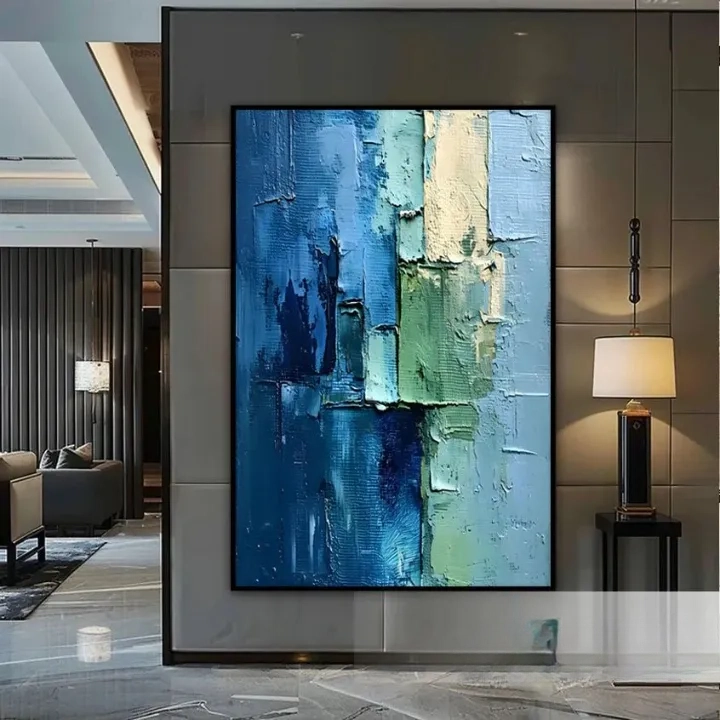 a large abstract painting with a blue and green color palette, displayed on a wall in a modern living room setting.