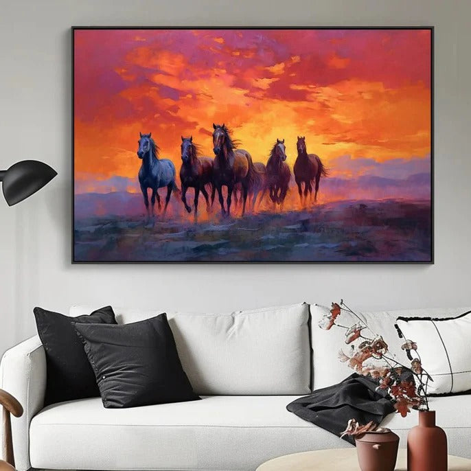 a group of horses running across a field at sunset, with a vibrant sky in the background.