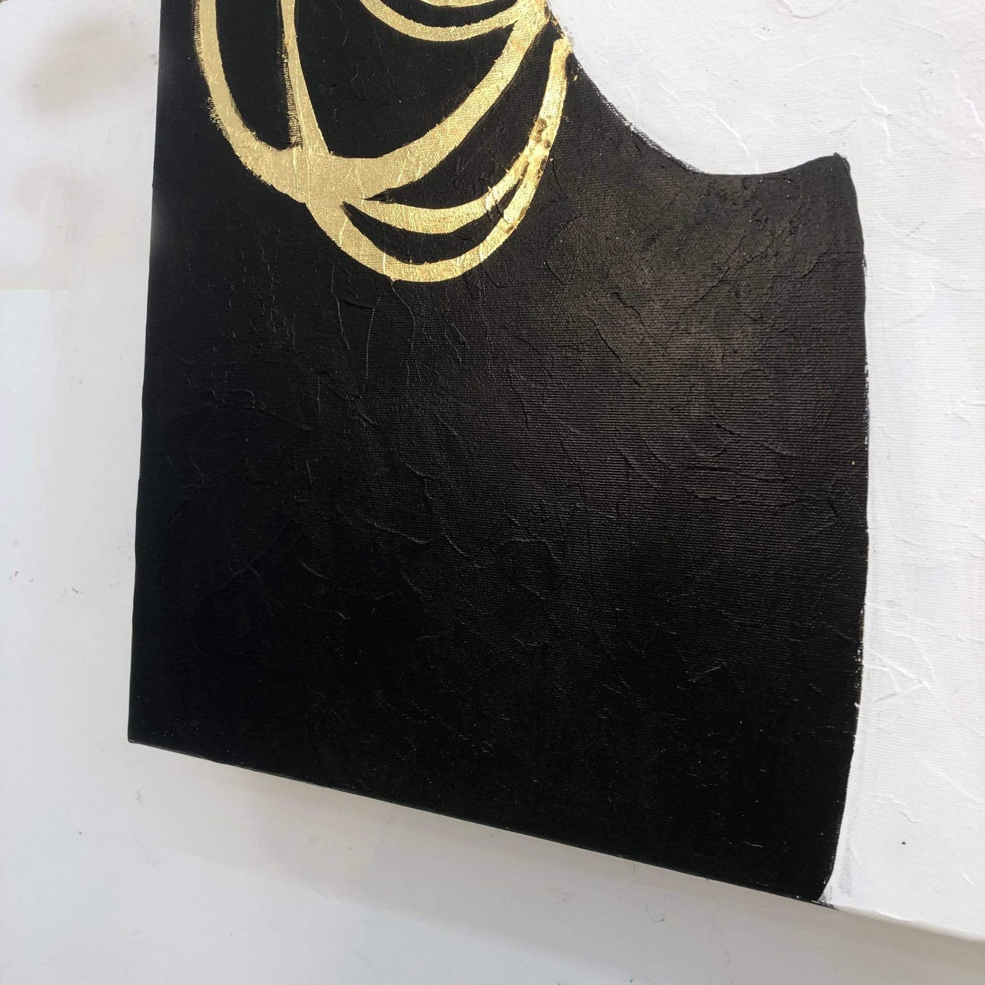 a black and gold painting on a white wall