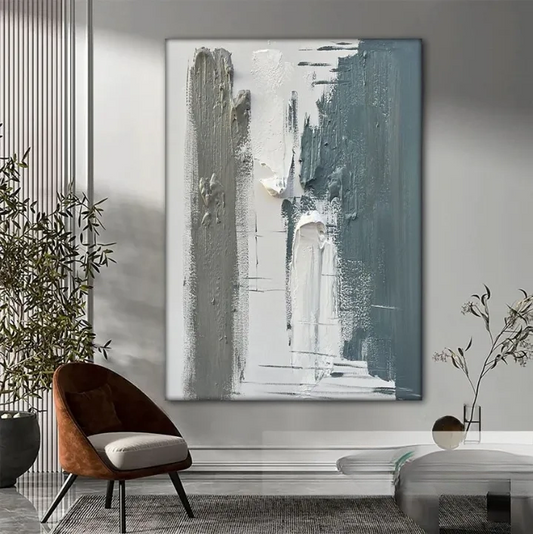 a modern living room with a large abstract painting hanging on the wall. The painting has a mix of gray and white colors, creating a striking contrast. The room is furnished with a brown armchair, a glass coffee table, and a potted plant, adding to the contemporary aesthetic.