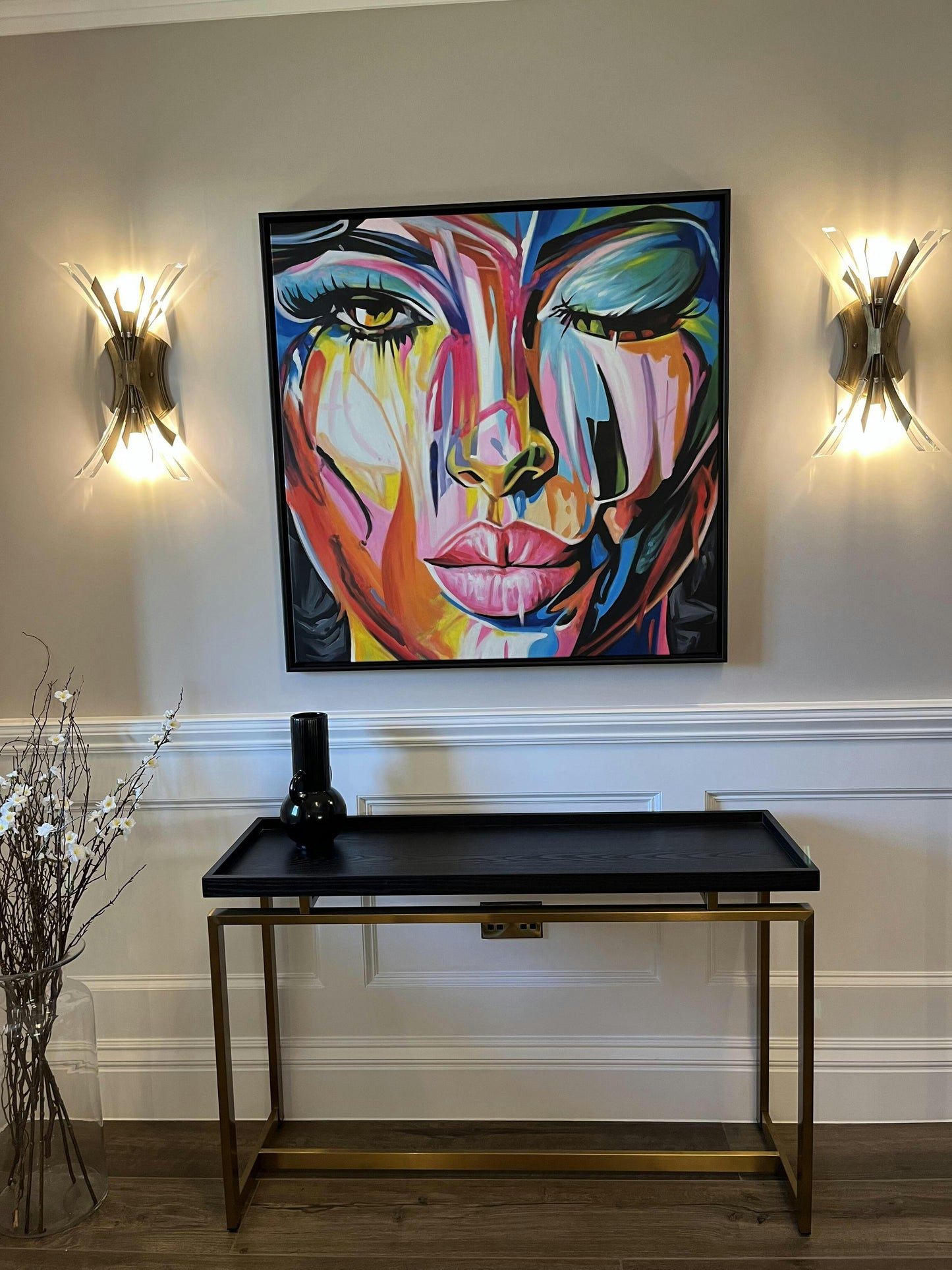 a painting hangs on the wall above a console table