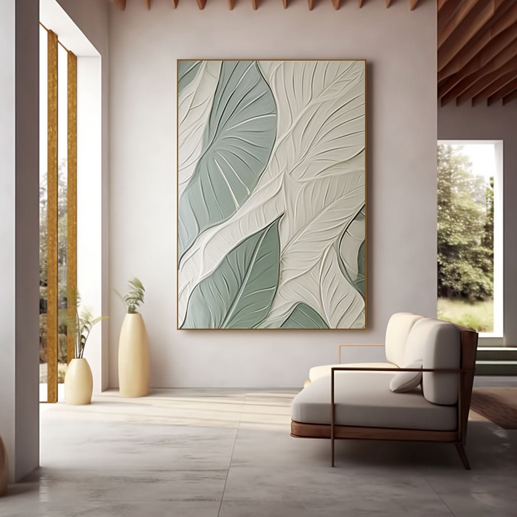 a modern living room with a large, abstract painting of green leaves on the wall. The room has a minimalist design, featuring a white sofa, a wooden coffee table, and a large window that provides a view of trees outside.