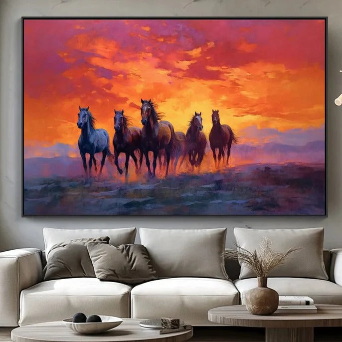 A large painting depicting a group of horses running across a field at sunset, with a vibrant orange and pink sky in the background.