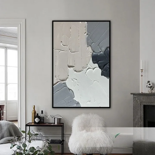 a living room with a large abstract painting hanging on the wall. The painting has a mix of white, gray, and black colors, creating a striking contrast. The room also includes a fireplace, a small table with a plant, and a plush white chair.