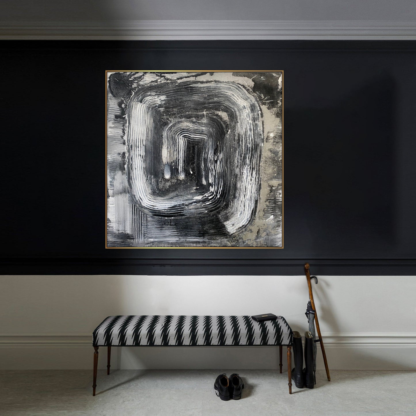 a black and white painting hanging on a wall next to a bench