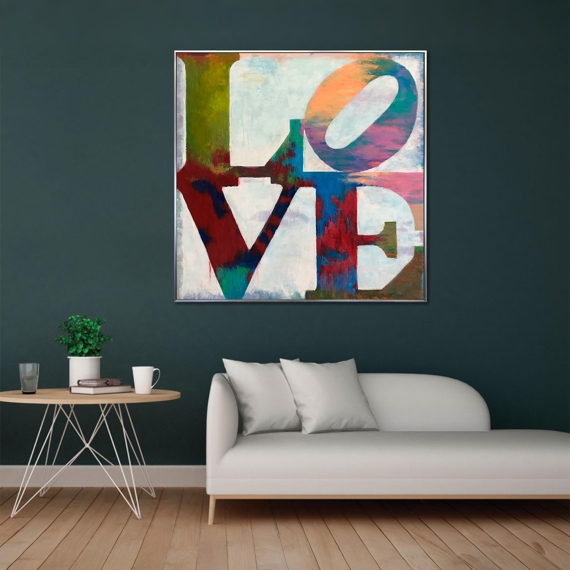 a large abstract painting of the word "LOVE" in bold, colorful letters hanging on a wall above a white couch in a living room setting.