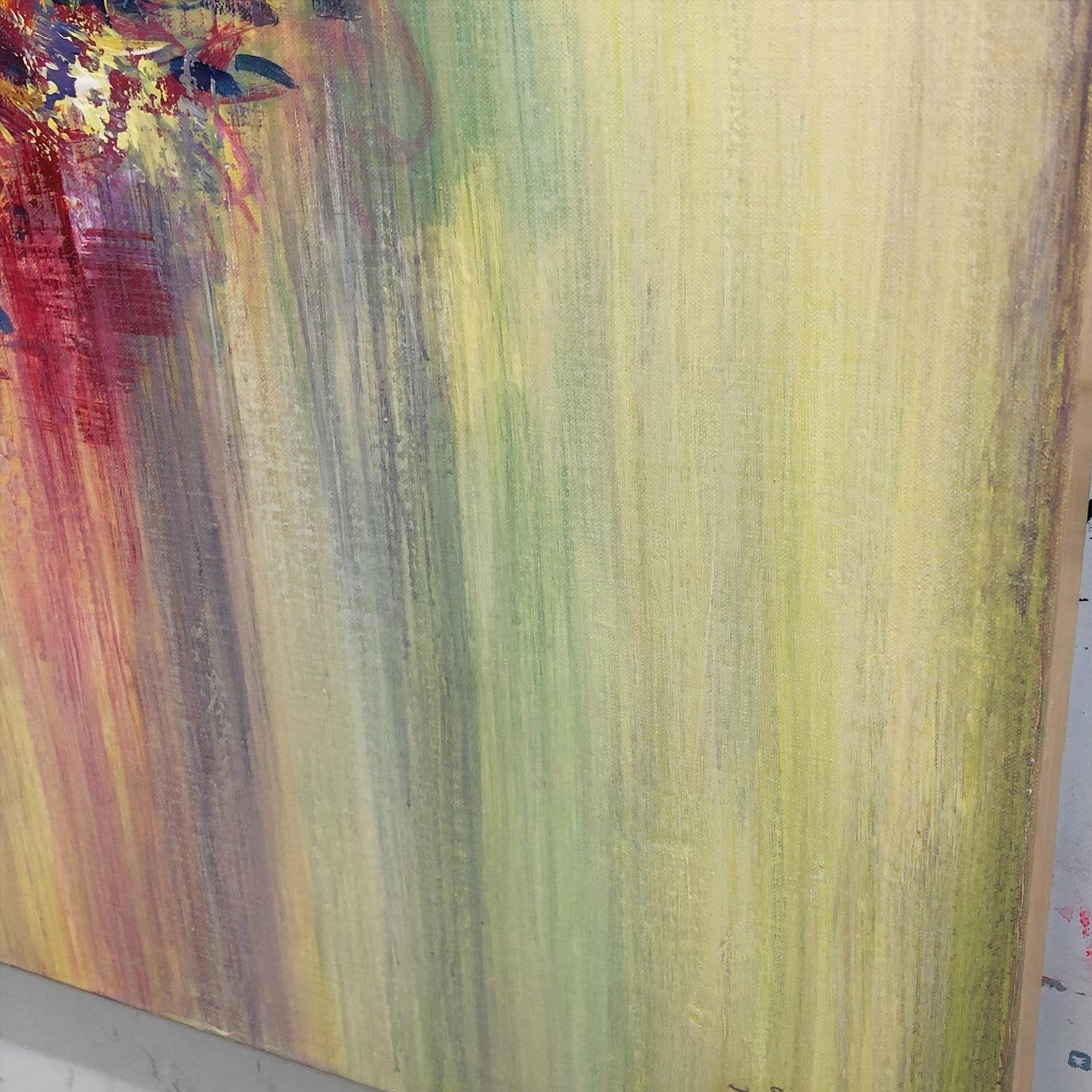 The image is a close-up of a colorful abstract painting with a vibrant mix of green, yellow, and red hues.