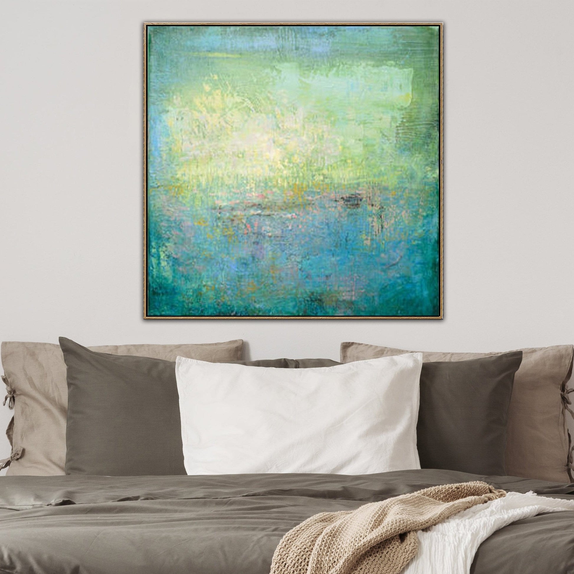 a large abstract painting hanging on a wall above a bed with a gray comforter and white pillows.