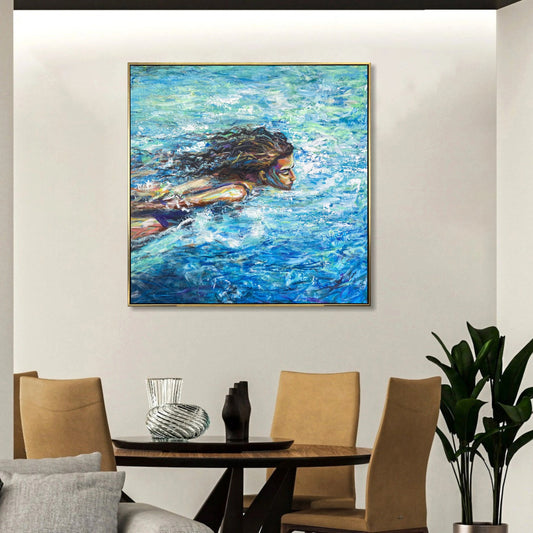 a large painting of a woman swimming in a blue ocean, hanging on a white wall above a wooden dining table with four chairs.