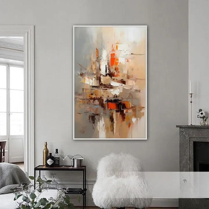 a large abstract painting hanging on a wall in a living room. The painting has a warm color palette with shades of orange, brown, and beige. The room has a cozy and inviting atmosphere, with a fireplace, a white chair, and a small table with various items on it.