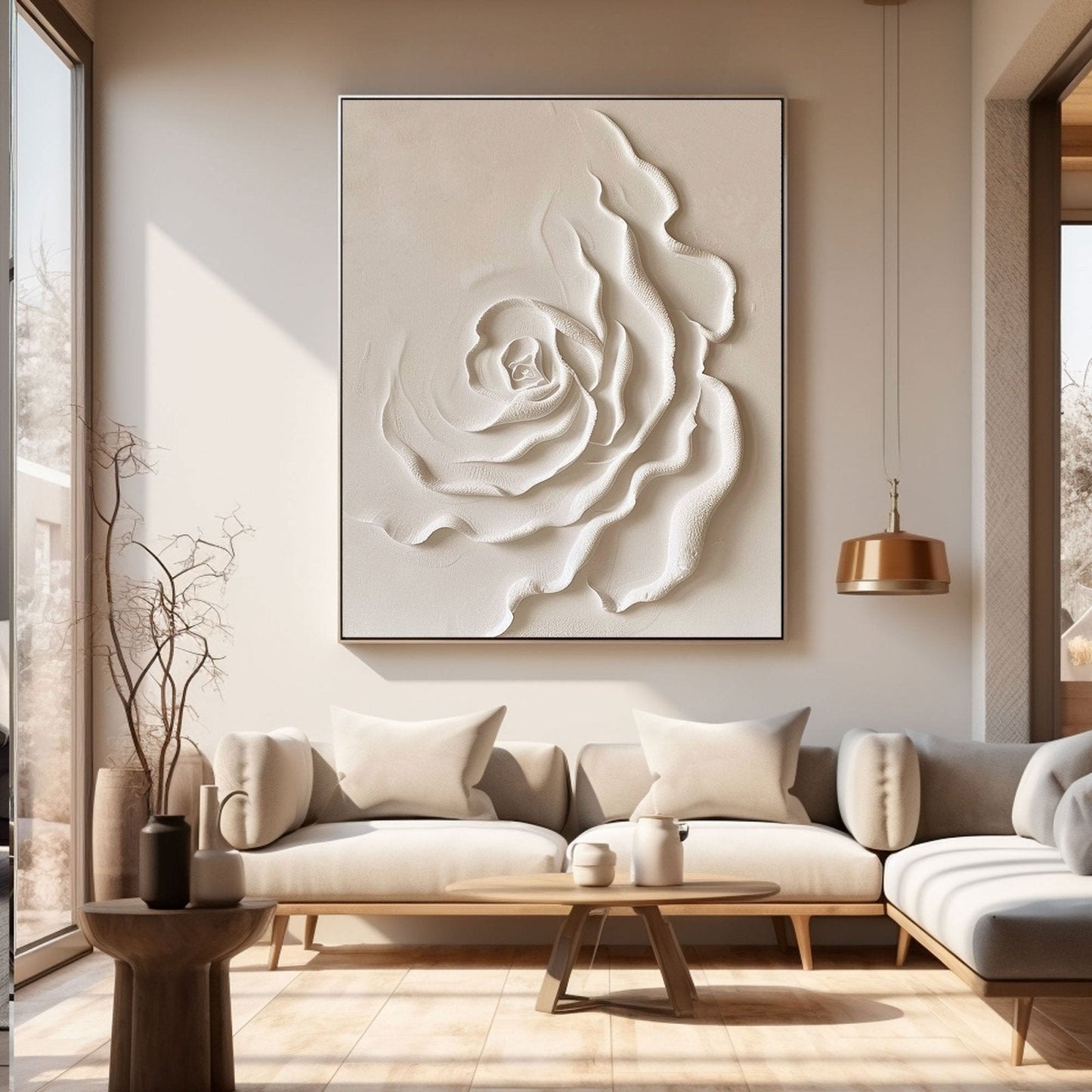 a modern living room with a large white floral artwork hanging on the wall above a gray sectional sofa. The sofa is positioned in front of a wooden coffee table, which also has a vase and a small plant on it. The room has a clean and minimalist design, with a large window providing natural light and a wooden floor.