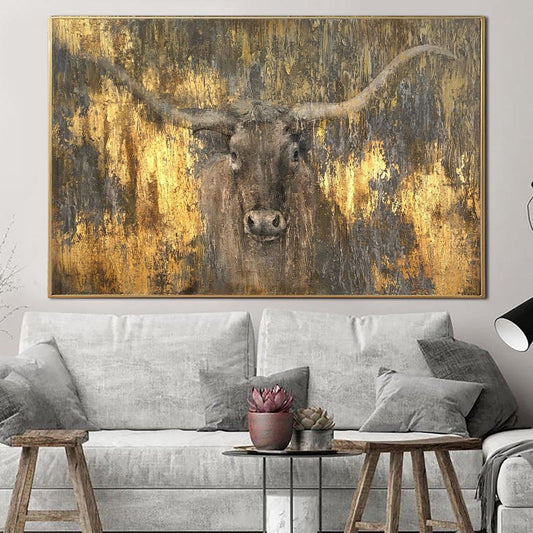 a large, gold-colored painting of a bull's head on a wall above a gray couch in a living room setting.