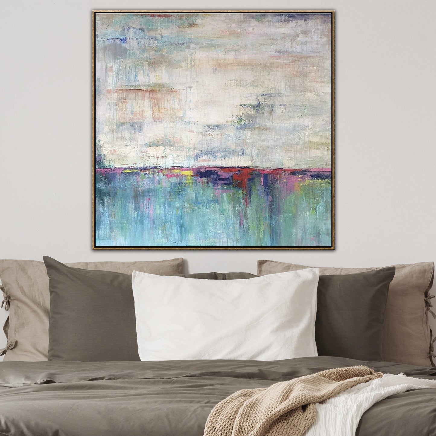 a large abstract painting hanging on a wall above a bed with pillows.