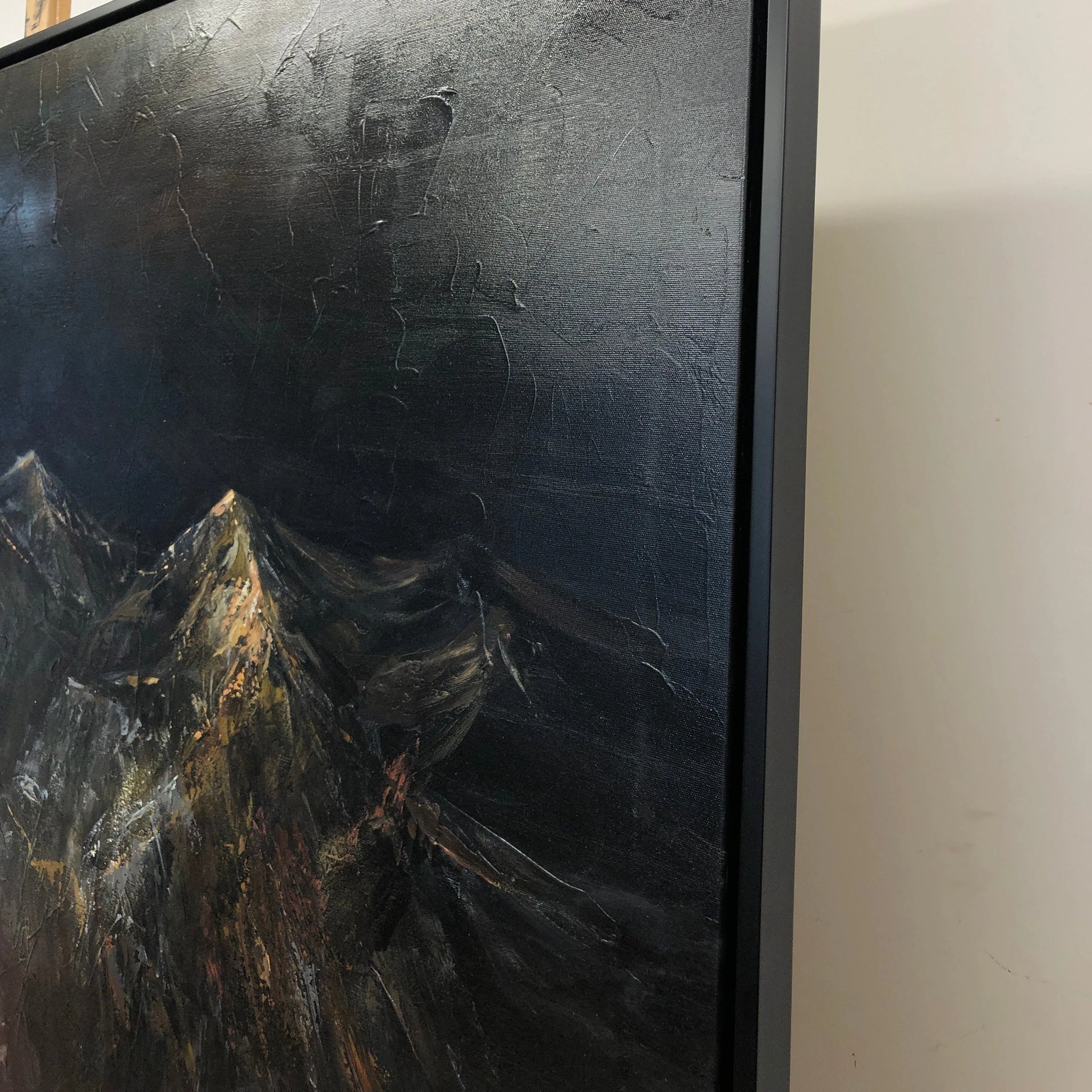 The image is a close-up of a painting depicting a mountainous landscape with dark, moody colors.