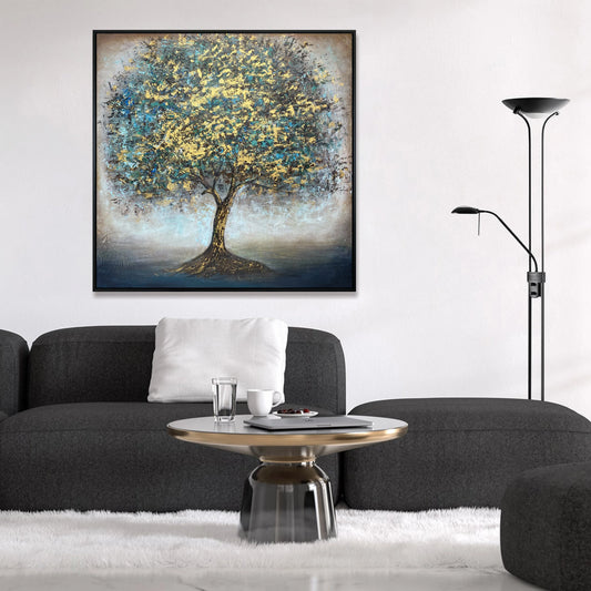 a modern living room with a large painting of a tree hanging on the wall above a gray sofa. The sofa is positioned in front of a coffee table, which has two cups and a remote control on it. The room also includes a floor lamp and a rug, creating a cozy and stylish atmosphere.
