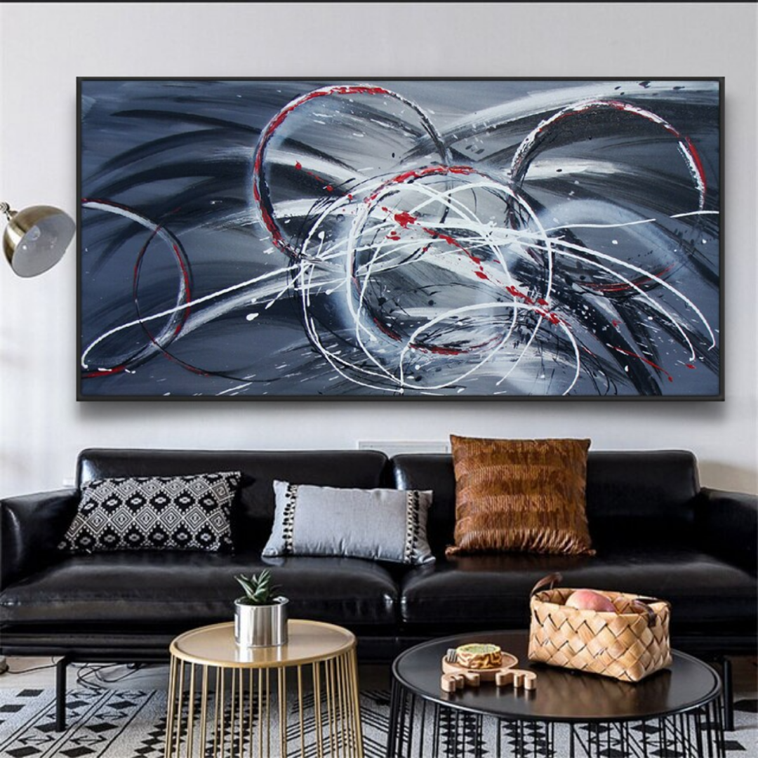 a living room with a black couch and a painting on the wall