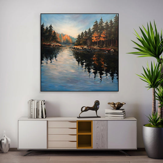 a large painting of a serene landscape with a lake and trees, hanging on a wall above a white cabinet with drawers. The cabinet also has a decorative horse figurine and some books on it. The painting is surrounded by greenery, including a potted plant and a vase, creating a harmonious and visually appealing interior design.