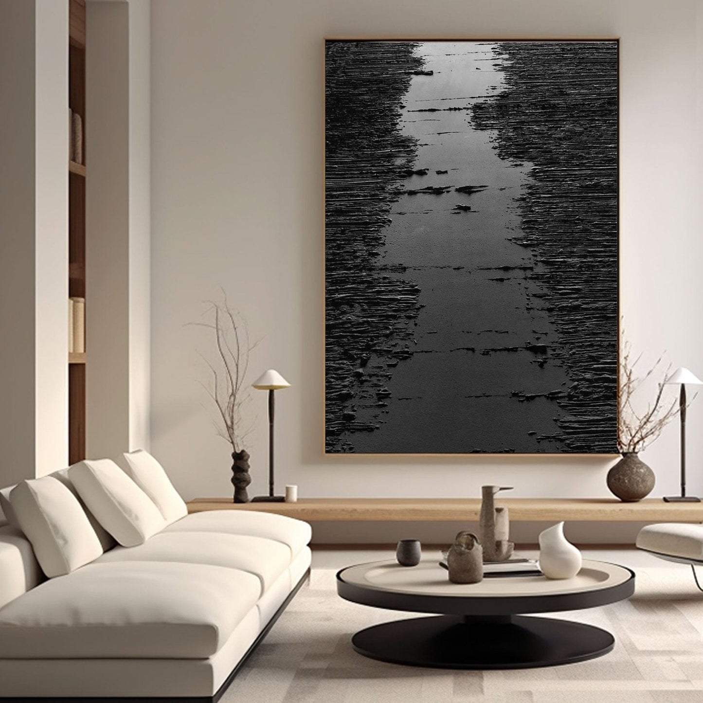 a modern living room with a large black and white abstract painting hanging on the wall above a white sofa. The room also features a coffee table with various decorative items, including a vase, a lamp, and a book.