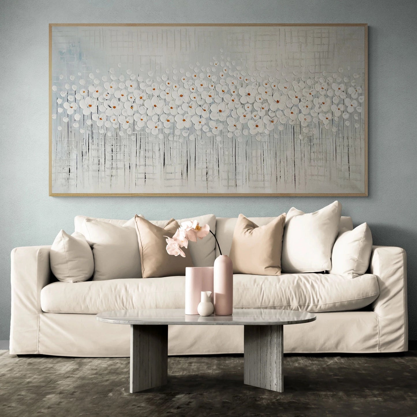 a living room with a white couch and a painting on the wall