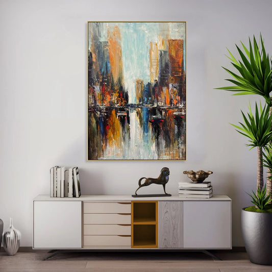 a modern art painting of a cityscape, hanging on a wall above a white cabinet with drawers. The painting is vibrant and colorful, depicting a bustling urban scene with tall buildings and a river flowing through the city. The cabinet below the painting has a decorative metal sculpture of a horse on top, adding a unique touch to the room's decor.