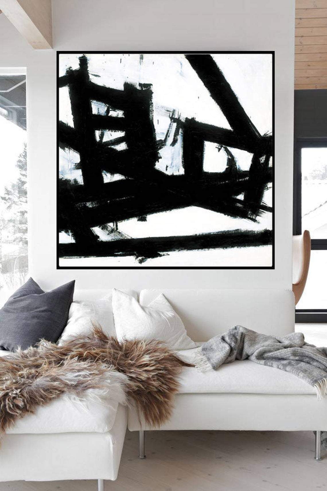 a living room with a white couch and a black and white painting on the wall