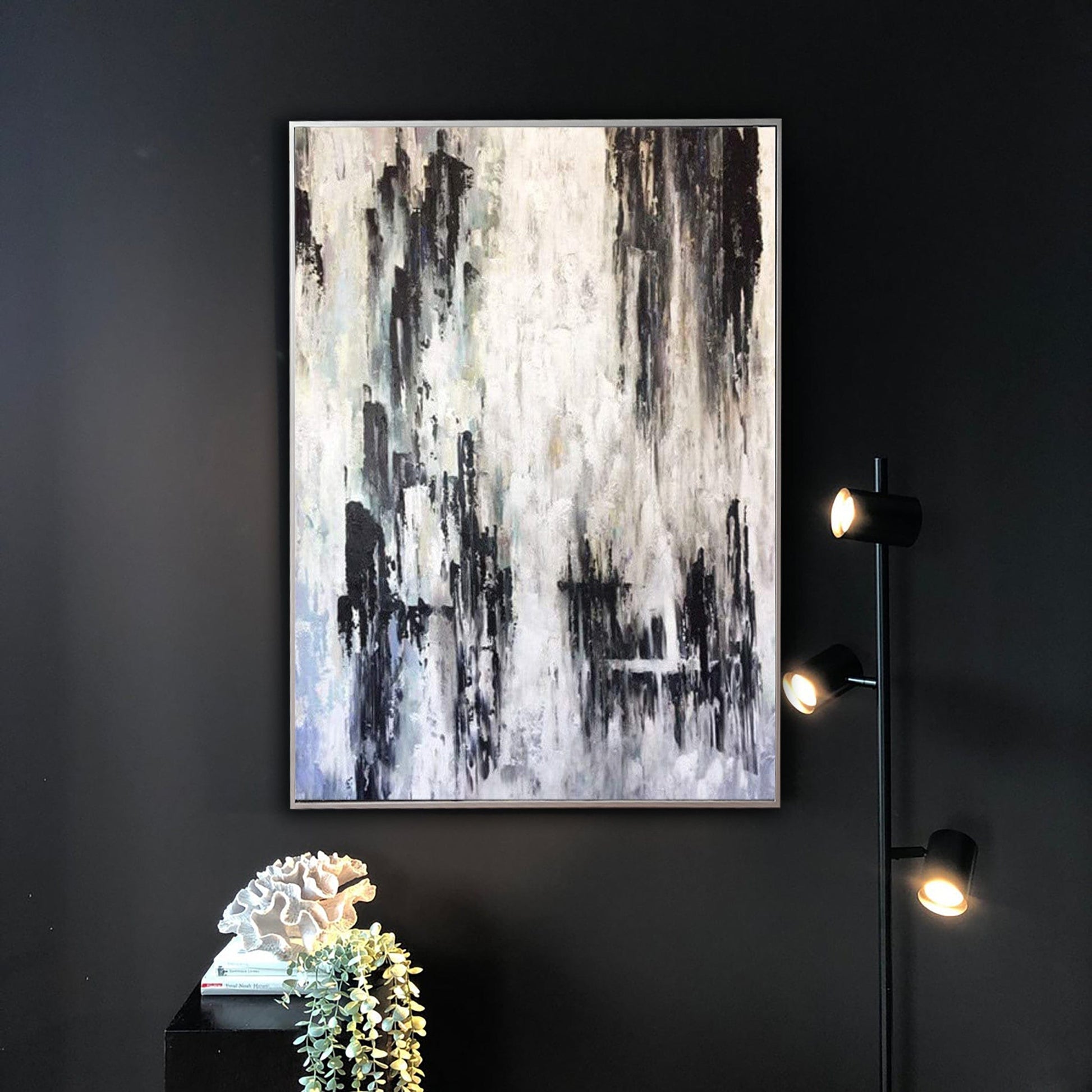 a large abstract painting hanging on a black wall, with a sculpture and a floor lamp in the foreground.