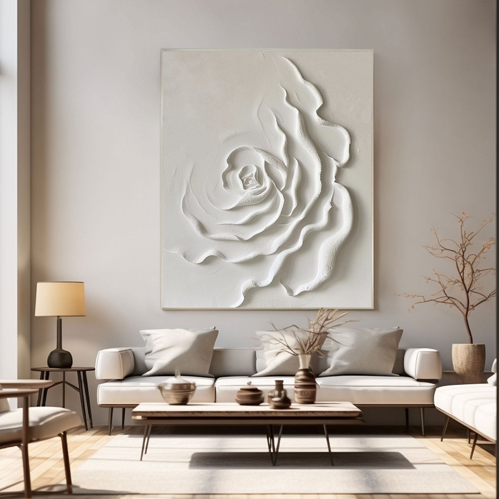 a modern living room with a large white floral artwork hanging on the wall above a white sofa. The room is furnished with a coffee table, a lamp, and a plant, creating a cozy and inviting atmosphere.