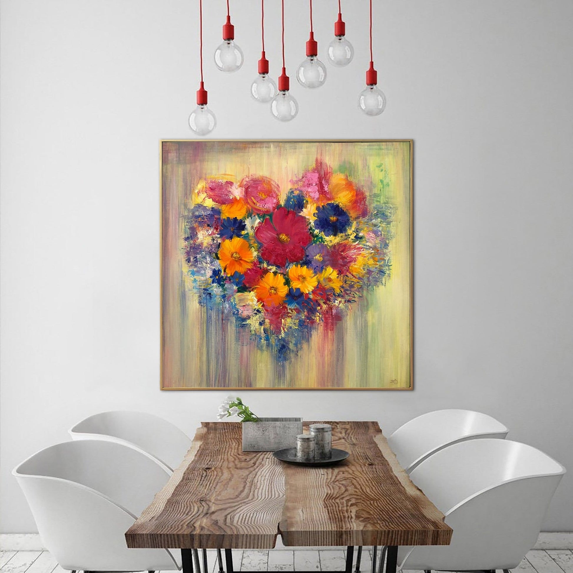 a wooden dining table with a vase of flowers on it, surrounded by white chairs. Above the table, there is a large painting of a heart-shaped arrangement of colorful flowers hanging on the wall.