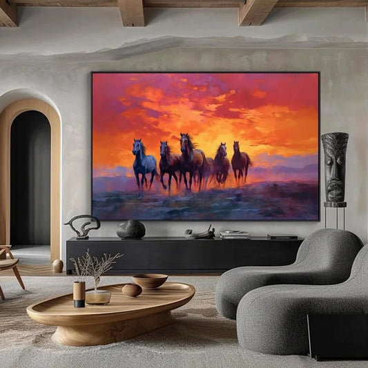 a modern living room with a large painting of horses running across a field at sunset as the focal point. The painting is hung on the wall above a wooden coffee table, which has a vase and a bowl on it. The room also features a gray sofa and a wooden side table.